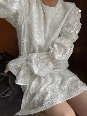 Vit blommig kortklänning med volang - Säljer nu min studentklänning i toppenskick! Den bästa att ha på studenten, så skön och perfekt att ha båda hela dagen men också på utpspringet!! Storlek 34/36! Köpte min för 900