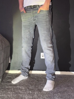Grå  jeans från Jack & Jones - Säljer ett par gråa jeans från Jack & Jones i storlek 28/32. Nästa helt oanvända. Går att köpa med ett par till jeans eller tröja med ett bättre pris.