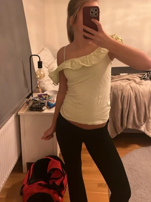 Ljusgul omlottopp från Holly & Whyte - Supersöt ljusgul topp från Holly & Whyte i storlek XS. Modellen är oneshoulder med volangdetalj längs halsringningen och smala axelband. Perfekt för dig som gillar en feminin och trendig look.