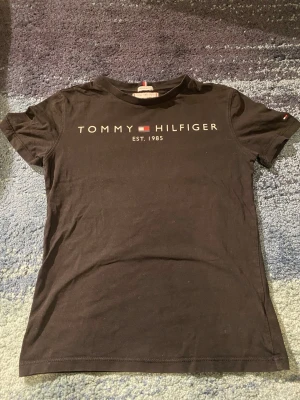 Tommy Hilfiger tröja  - Tommy Hilfiger t-shirt – Storlek XS 🖤 Stilren och klassisk Tommy Hilfiger t-shirt i svart med logga framtill 👕 Tidlös modell som funkar perfekt till både vardag och mer uppklädda outfits 💫 ✔️ Storlek: XS ✔️ Skick: Använd men i bra skick ✔️ Passform: Slim/klassisk ✔️ Original Tommy Hilfiger En garderobsklassiker som är lätt att matcha med allt 👖👟 Hör av dig om du vill ha fler bilder eller mått 📩😊
