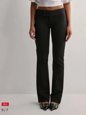 Low Waist kostymbyxor - Snygga svarta byxor med låg midjat. Byxorna har två knappar framtill och är i ett stretchigt material som sitter skönt. Helt nya aldrig använt😊