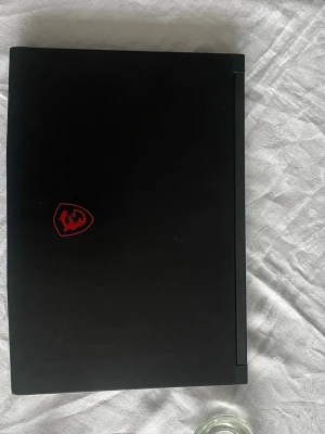 MSI Gaming Laptop - Jag säljer min MSI gaming laptop med Intel Core i5-processor och NVIDIA GeForce RTX-grafik. Svart design med röd bakgrundsbelyst tangentbord och MSI-draklogga. Utrustad med HDMI-port och robust kylning. Gott skick, Jag säljer den för spara upp till et ps5