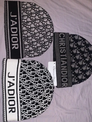 Christian Dior svartvit mönstrad mössa - Säljer en stickad mössa från Christian Dior med svartvitt grafiskt mönster och bred kant med texten 'J'ADIOR' eller 'CHRISTIAN DIOR'. Mössan har en clean och trendig look som sticker ut och passar perfekt till kalla dagar.