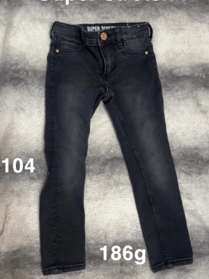 Svarta stretchiga jeansbyxor barn - Säljer ett par svarta stretchiga jeansbyxor för barn i storlek 104. Byxorna har klassisk femficksdesign, knapp och dragkedja framtill. Perfekta för dig som vill ha bekväma och snygga jeans till vardags.🌸 Använda en kort stund, super stretch står det i. Storlek 104