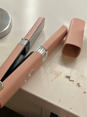 Rosa plattång med USB-laddning - Säljer en modern trådlös plattång i matt rosa med silverdetaljer. Den är elektrisk och laddas med USB-C, perfekt för att få en snygg look i håret. Stilren och smidig design.