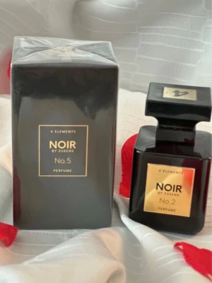 Noir by Essens parfym (Oud Wood de Tom Ford)  - Upptäck 4 Elements Noir by Essens No. 5 och No. 2. Volym: 50 ml. Ingredienser: Alcohol denat., parfum (fragrance), aqua, linalool, coumarin, benzyl benzoate, cinnamyl alcohol, limonene. Tillverkad i Tjeckien. Snygg design som sticker ut i badrumshyllan.