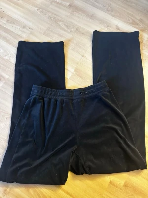 Svarta mjukisbyxor från Gina Tricot - Mysiga svarta mjukisbyxor från Gina Tricot i mjukt material. Byxorna har resår i midjan och raka ben för en chill och avslappnad look. Perfekta för att hänga hemma eller när du vill vara bekväm hela dagen.