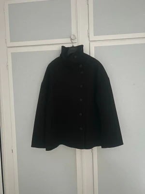 Svart kappa från Pernilla Wahlgren - Supersnygg svart kappa med knappar från Pernilla Wahlgren. Sitter snyggt oversize på mig som är 170🌸 Liknar arket jackkorna lite och man kan knäppa den på olika sätt🤍perfekt vinter vår och höst kappa  Helt ny Kolla in mina andra artiklar!!