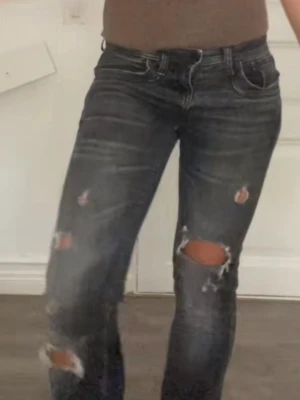 Lågmidjade Ltb jeans med hål  W24 L34 - Säljer ett par svarta Ltb jeans med slitna detaljer och stora hål vid knäna. Jeansen har en klassisk femficksmodell, normal passform och är tillverkade i jeansmaterial. Perfekta för dig som gillar en edgy och avslappnad stil.