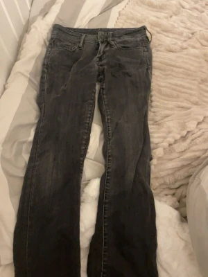 Svarta lågmidjade jeans i storlek 25 - Säljer ett par svarta jeansbyxor i storlek 25. De har klassisk femficksdesign och är tillverkade i bomull med lite elastan för extra stretch. Snygg passform och utsvängda ben, perfekta till din vardagsstil.