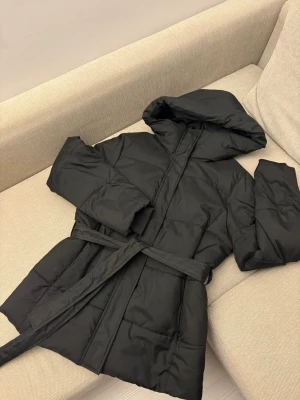 Svart vinterjacka från Ellos - Säljer en svart vinterjacka från Ellos i storlek S, den är köpt 2024 och har använts med kärlek och sparsamt. Jackan har huva och bälte i midjan💕Väldigt stilren vinterjacka som matchar alla🥰 Det finns inga fel på jackan🫶