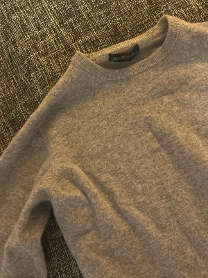 Beige kashmirtröja från Alan Paine - Mysig beige kashmirtröja  från Alan Paine med rund halsringning och lång ärm. Tröjan är supermjuk och har en klassisk, enkel design som passar perfekt till lager-på-lager under kyliga dagar den har litet hål men går att laga