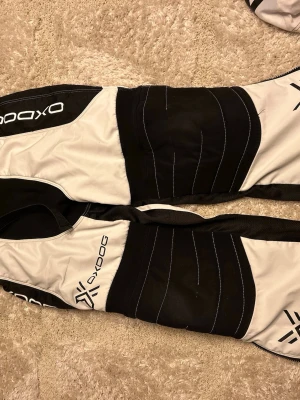 Målvakt kläder oxdog + oxdog hjälm - Svart vita målvakts kläder plus svart vit oxdog hjälm. Detta är begagnade kläder som jag har köp men använt 1 gång, byxor-bra Skick och kostar 700 kr tröja-bra skick, finns gammalt tryck kvar men trycket kommer att tas bort av oss om någon är intresserad av köp, kostar 500 kr. Hjälm-bra skick, kuddarna som tillhör hjälmen kan försökas tvättas av oss vid köp men nya kuddar får man köpa själv, hjälmen kostar 600 kr. ⚠️(paket pris finnas även där allt ingår för 1 700 kr) ⚠️!!!!