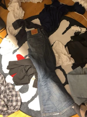 Levi's 517 bootcut jeans blå - Säljer ett par klassiska Levi's 517 jeans i blå denim med bootcut-passform. Jeansen har en snygg tvätt med slitningar och den ikoniska Levi's-lappen bak i midjan. Perfekta för dig som gillar retrostil och vill ha ett par jeans med lite vidare ben nertill.