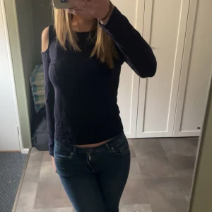 Mörkblå offshoulder långärmad topp - Säljer en mörkblå långärmad topp med offshoulder-detalj på axlarna. Snygg och enkel modell med rund halsringning och figurnära passform. Perfekt för dig som vill ha en stilren men ändå trendig look.