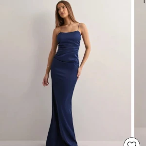 Marinblå Balklänning med tunna axelband - Elegant marinblå långklänning från Nelly. Aldrig använd. Säljer den eftersom jag fick låna en annan av min kompis. Prislappen sitter kvar. Köpt för 899 kr. Pris går att diskuteras 💕