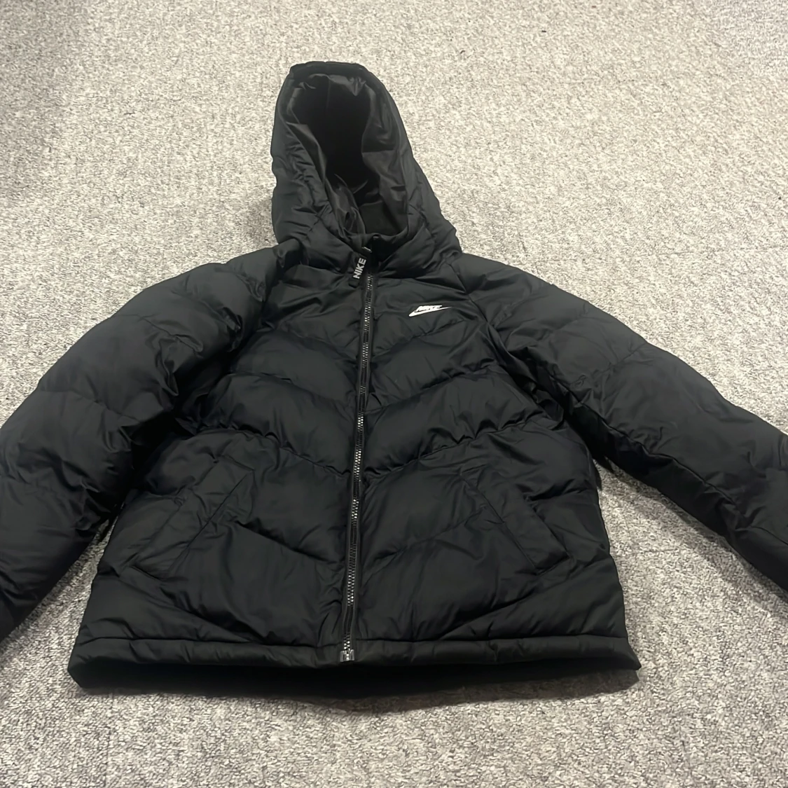 Svart pufferjacka från Nike med huva