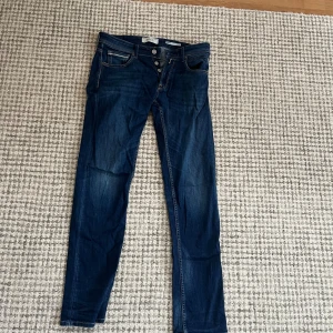 Replay Grover straight jeans blå - Säljer ett par mörkblå Replay Grover jeans med straight fit. Klassisk femficksmodell, snygga kontrastsömmar och knäppning med knappar. Märkespatch bak i midjan och diskret sliten look. Perfekta jeans för dig som gillar en tidlös stil. Måtten är W30 och L32