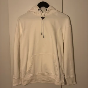 Vit hoodie från Prada med logga - Om det önskas fler bilder så är det inga problem. Tröjan har en fläck nedanför kragen men den märks bara i vissa ljussättningar.