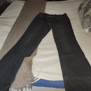 Grå bootcut jeans från Jsfn Denim - Snygga grå jeans från Jsfn Denim med bootcut passform och klassisk femficksdesign. Jeansen har ljusa kontrastsömmar och dekorativa broderier på bakfickorna. Perfekt för dig som gillar en avslappnad men stilren look.