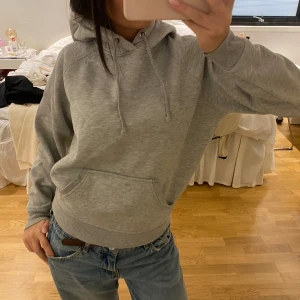 Grå hoodie från BikBok XS - Klassisk grå hoodie från BikBok i storlek XS. Tröjan har huva med snörning, magficka och ribbade muddar vid ärmslut och nederkant. Perfekt för en chill och avslappnad stil. Mjuk insida i fleece-liknande material.