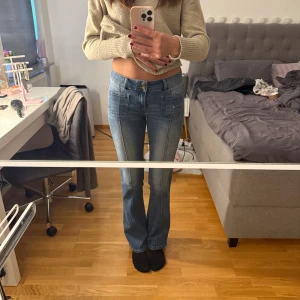 Blå bootcut jeans från Madlady - Säljer ett par blå bootcut jeans från Madlady med låg midja. Jeansen har framfickor, snygga detaljer på bakfickorna och klassisk knappstängning. Materialet är jeans med lätt tvättad look och de sitter riktigt snyggt. Storleken är 36/tall. Säljer endast då jag tycker de är litteeee korta på mig som gärna har 90 i innerben. Dessa är 84 Elelr 86 är inte helt säker! Priset går att diskutera