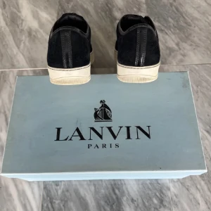 Svarta sneakers från Lanvin med lackad tå - Säljer ett par svarta sneakers från Lanvin. Använda ca 10 ggr. Box medföljer ej. Storlek uk 9 typ som 43-44. Pris är förhandlingsbart. Har liten defekt på framsidan som knappt syns