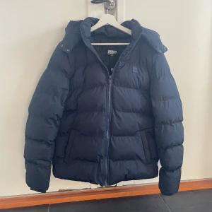 Uraban classic pufferjacka - Tja! Säljer denna snygga vinterjackan i helt nytt skick | Den är väldigt varm och praktisk då man kan ta av luvan om det blir varmt men även knäppa åt den om de bli kallare ( se på bild ) | Pris kan diskuteras vid snabb affär, hör av er vid funderingar