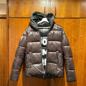 Mörkbrun pufferjacka från Save The Duck - Säljer vinterjacka från save the duck som jag köpt för att ha i vinter. Kände tidigt att den var för liten men tänkte att man skulle vänja sig vilket jag ej gjorde. Enbart använt den 2 gånger och den är köpt från Care of Carl för 3000kr. Den är alltså i väldigt fin kvalité och helt i nyskick.