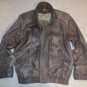 Vintage brun skinnjacka/läderjacka - unisex bomberjacka - nappaläder - Vintage brun skinnjacka i lite av en bomberjackamodell. Vet inte om den kan komma från Dennis päls och skinn AB. Mjukt nappaläder med väldigt fin patina efter användning. Vet inte vad det är för storlek men skulle tippa M/L - se bilder för mått. Passar fler storlekar beroende på hur man vill att den ska sitta, och är unisex, skulle jag säga. Stängs med både dragkedja och knappar (fyra knappar saknas, men det är lätt att sy dit nya om man vill).