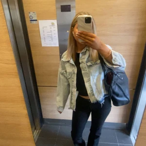 Ljusblå oversized jeansjacka - Säljer en ljusblå oversized jeansjacka med klassisk krage och knappar framtill. Jackan har två bröstfickor med lock och en rå, fransig nederkant för en trendig look. Perfekt att slänga över en t-shirt eller hoodie.