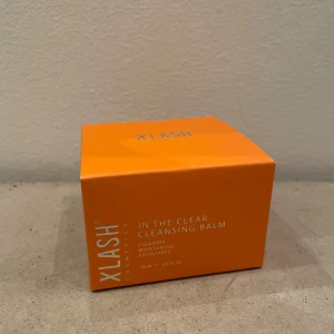 Xlash In The Clear Cleansing Balm - Xlash In The Clear Cleansing Balm i en snygg orange förpackning, 100 ml. Denna balm rengör, återfuktar och exfolierar huden. Innehåller oljor, smör och fruktextrakt som förvandlas till en lyxig olja vid applicering. Perfekt för att ta bort smink och smuts.
