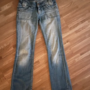 snygga low waist bootcut jeans - Super snygga riktiga low waist blåa/ljusblåa bootcut jeans med unik design. säljer pga att de tyvärr va för små för mig. köptes för ungefär 400kr