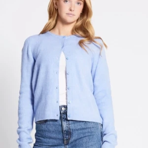 Ljusblå kofta från 157, M - Superfin ljusblå kofta med rund hals och knappar framtill. Tröjan har lång ärm och är stickad i mjukt material som känns skönt mot huden. Perfekt att slänga över en t-shirt och matcha med jeans för en chill look. Storlek M. Oanvänd. 