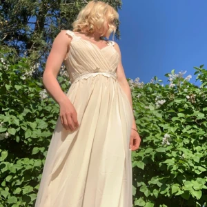 Ljus långklänning med spetsdetaljer - Superfin ljus långklänning perfekt till studentbal. Klänningen har spetsdetaljer på axelbanden och runt midjan samt öppen rygg med spets. Endast använd en gång så fortfarande i fint skick. Rekommenderas till någon som är runt 160 cm.💕