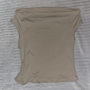 Tre offshoulder tubtoppar i neutrala färger - Säljer tre stilrena offshoulder tubtoppar i beige, brun och svart. Alla ärmlösa och i stretchigt, mjukt syntetmaterial som sitter tight och smickrande. Aldrig använda, alltså nytt skick. Perfekta att matcha med jeans eller kjol för en clean look💕 3-pack: 80kr, 1-pack: 30kr