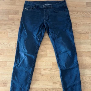 Mörkblå jeans från Diesel Industry - Snygga mörkblå jeans från Diesel med klassisk femficksdesign och diskret Diesel Industry-detalj på myntfickan. Jeansen har en rak passform och är tillverkade i slitstarkt denimtyg som sitter skönt hela dagen. En defekt på vänster byxben men inget man tänker på vid använding. Nypris 1300, mitt pris är inte hugget i sten, kan gå ner i pris vid snabb affär