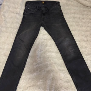 Två par Lee jeans, svart & blå - OANVÄNDA!!!! (Båda två ingår i priset!)Säljer två par Lee jeans, ett par i mörkgrått och ett par i klassisk blå denim. Båda har femficksdesign, raka ben och Lee-logga på bakfickan. Jeansen är i stretchigt jeanstyg och har normal passform, perfekta för dig som gillar stilrena och tidlösa jeans.