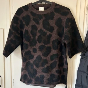 Leopardmönstrad stickad tröja H&M - Stickad tröja från H&M i brunt och svart leopardmönster. Tröjan har korta ärmar, rund halsringning och en loose fit. Perfekt för dig som vill sticka ut med en trendig look. Ny utan prislapp.