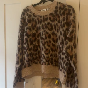 Leopardmönstrad stickad tröja Kappahl - Säljer en stickad tröja från Kappahl med leopardmönster i bruna och beige toner. Tröjan har rund halsringning, långa ärmar och ribbade muddar. Perfekt för dig som vill sticka ut lite extra i höst och vinter!
