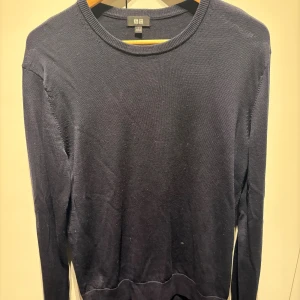 Svart tröja från Uniqlo i bomull - En stilren svart tröja från Uniqlo i mjuk bomull. Tröjan har rund halsringning, långa ärmar och ribbade muddar vid hals, ärmslut och nederkant. Perfekt för lager-på-lager och enkel att matcha med allt.