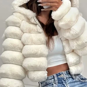 Vit croppad puffer pälsjacka med huva - Säljer en fluffig och croppad pufferjacka i vit fuskpäls med huva. Jackan har breda, vadderade sektioner och dragkedja framtill. Perfekt för dig som vill sticka ut och hålla dig varm med stil.