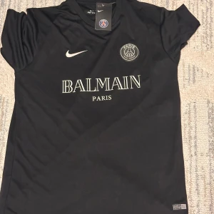 Svart PSG x Balmain fotbollströja Nike - Helt ny med etikett . Tröjan har korta ärmar, rund hals och tryck med Balmain Paris på bröstet samt PSG-logga. Materialet är lätt och andas, perfekt för träning eller match. Helt ny med etikett 