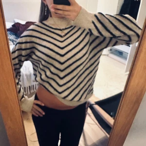 Beige och svart randig stickad tröja - Supermysig stickad tröja i beige med svarta ränder i ett snyggt V-mönster. Inga större defekter, däremot lite lite nopprig vid ärmarna ( bild 2 )