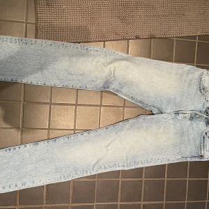 Levi's 501 ljusblå jeans W28 L32 - Säljer ett par klassiska Levi's 501 jeans i ljusblå tvätt. Modellen har raka ben, knappgylf och fem fickor. Jeansen är tillverkade i slitstark bomullsdenim och har den ikoniska läderpatchen bak i midjan. Perfekta för en avslappnad och tidlös look.