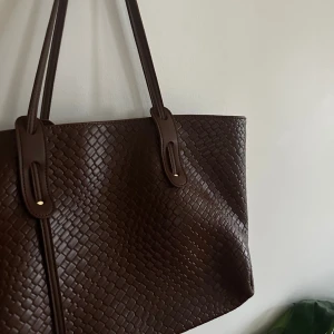 Brun flätad väska - Fin, rymlig brun flätad väska. Rymmer både dator och a4 block!