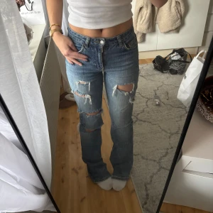 Ljusblå ripped jeans - Ljusblå ripped jeans från Perfect Jeans med snygga slitningar och hål på båda benen. Modellen är midwaist, raka ben och klassisk femficksdesign. Jeansen är tillverkade i ett bekvämt material och ger en somrig look☀️I storlek 32 men passar mig som brukar ha 34/xs💕 Uppfransade i botten på benen då jag är väldigt kort