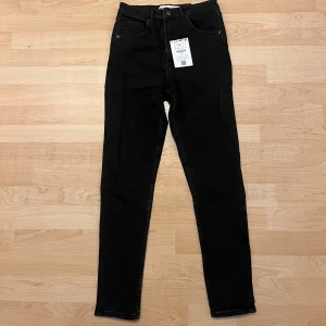 Svarta skinny jeans från Bershka - Snygga svarta jeans från Bershka med klassisk femficksdesign och hög midja. Modellen är skinny och sitter tight längs benen
