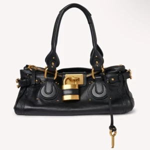 Chloé Paddington handväska i skinn - Ikonisk Chloé Paddington handväska i skinn med stora guldfärgade metalldetaljer och hänglås. Finns i svart, mörkbrun och beige. Väskan har dubbla handtag, dragkedja och dekorativa spännen. Perfekt för dig som vill ha en statementväska med lyxig känsla.