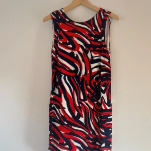 Färgstark mönstrad klänning Stockh LM - Säljer en ärmlös kortklänning från Stockh LM i storlek 36. Klänningen har ett coolt abstrakt mönster i rött, marinblått och vitt. Den är figurnära upptill och har dragkedja i sidan för enkel påklädning. Perfekt för dig som gillar att sticka ut!